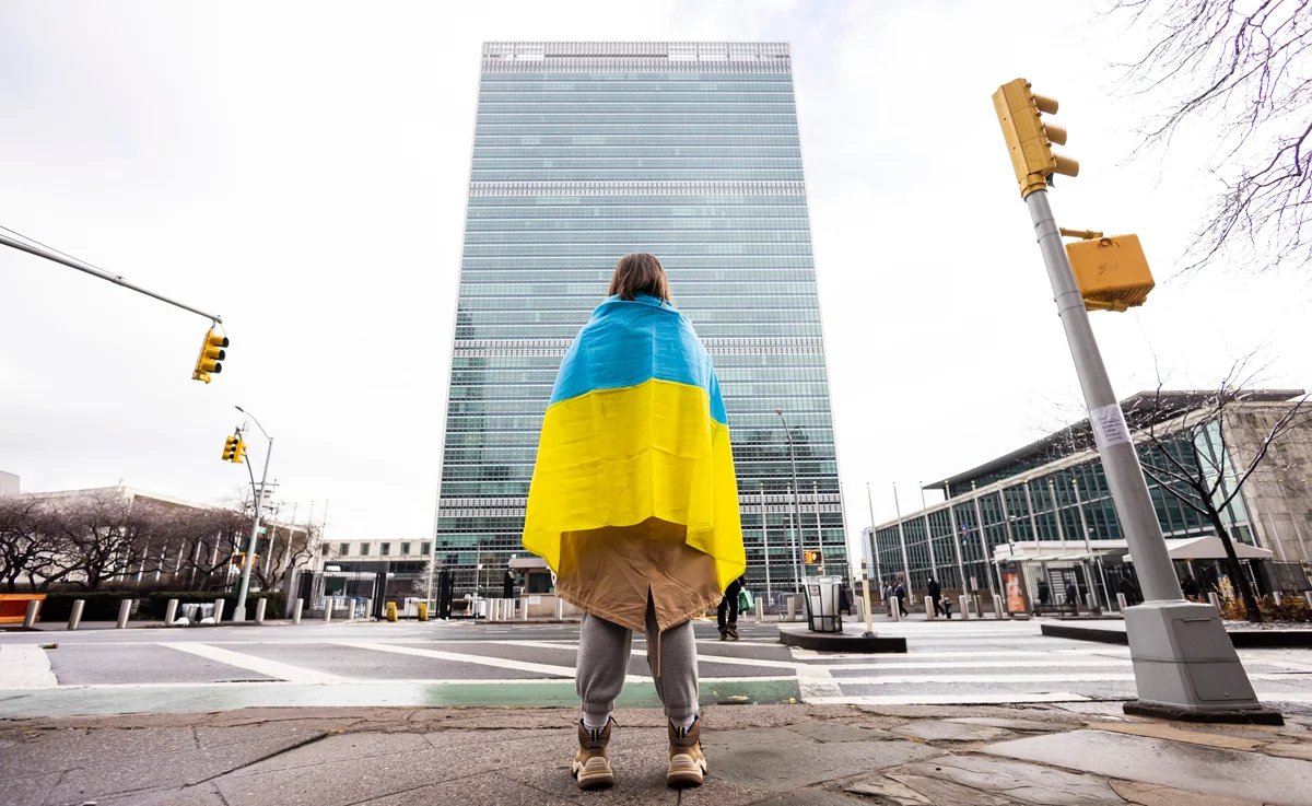 Женщина с украинским флагом стоит напротив штаб-квартиры ООН, Нью-Йорк, 25 февраля 2022 года. Фото: Justin Lane / EPA