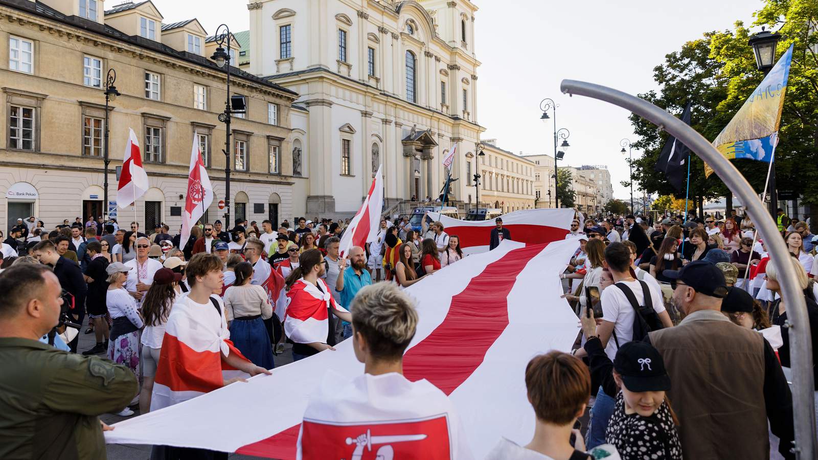 Участники митинга, посвященного шестой годовщине президентских выборов в Беларуси 2020 года, держат большой белорусский бело-красно-белый национальный флаг. Варшава, Польша. 9 августа 2026 года. Фото: SOPA Images Limited / Alamy Live News / Vida Press<br>