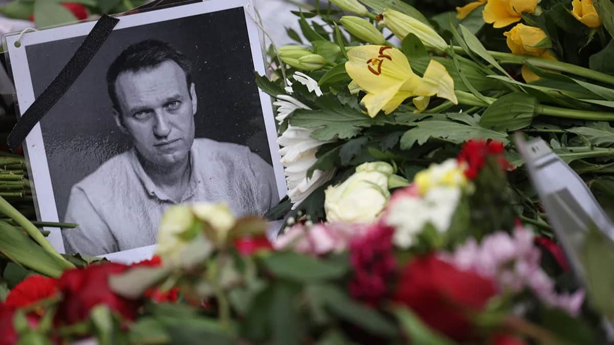 Портрет покойного Алексея Навального между цветами во время митинга перед посольством России в Берлине, 18 февраля 2024 года. Фото: Clemens Bilan / EPA-EFE