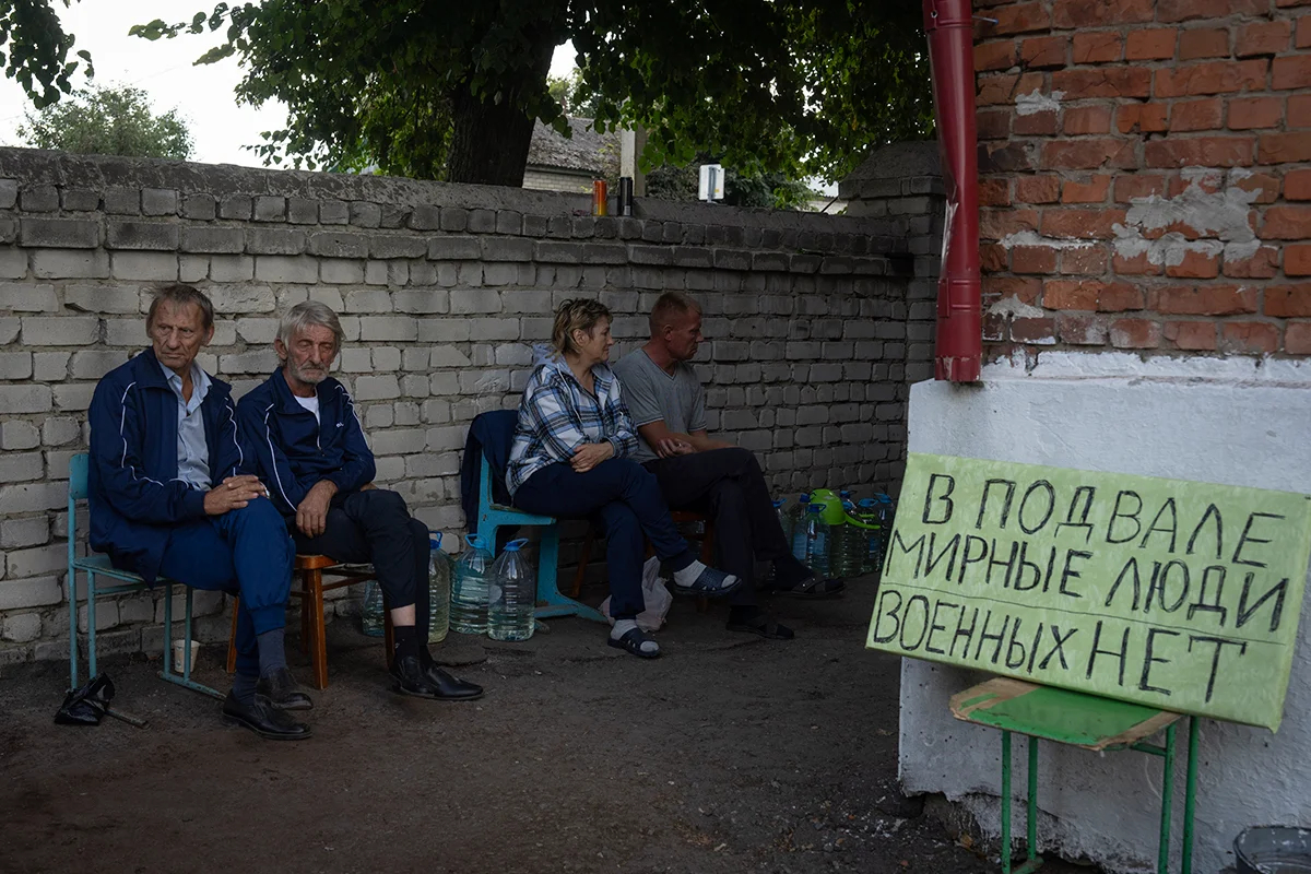 Местные жители возле убежища в Судже, Россия, 16 августа 2024 года, рядом с табличкой с надписью «Гражданские лица в подвале. Военных нет». Фото: AP / Scanpix / LETA
