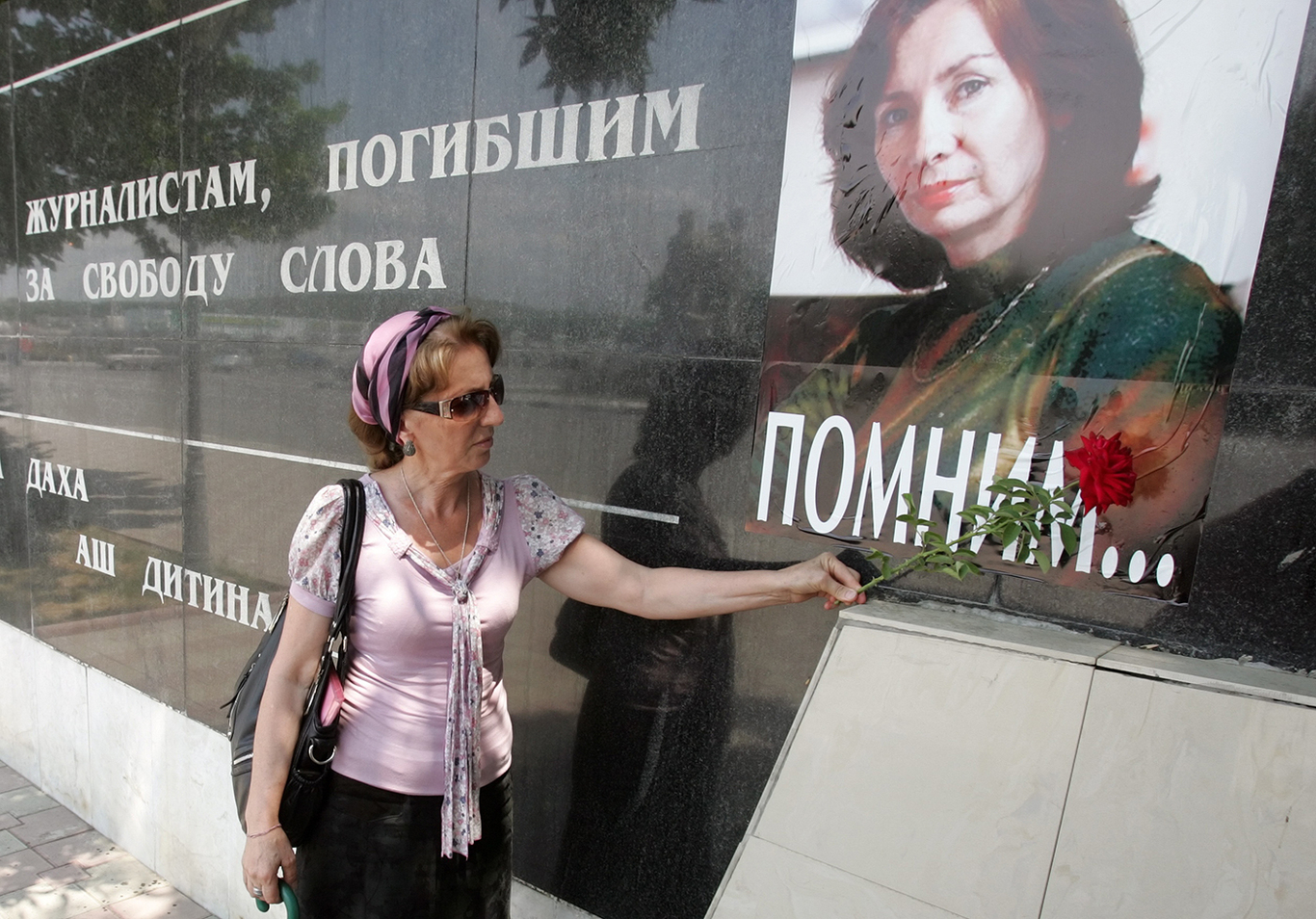 4.Чеченская женщина возлагает цветы к плакату с изображением Натальи Эстемировой с надписью «Мы помним» в Грозном. Чечня, Россия. 15 июля 2011 года. Фото: Kazbek Vakhayev / EPA