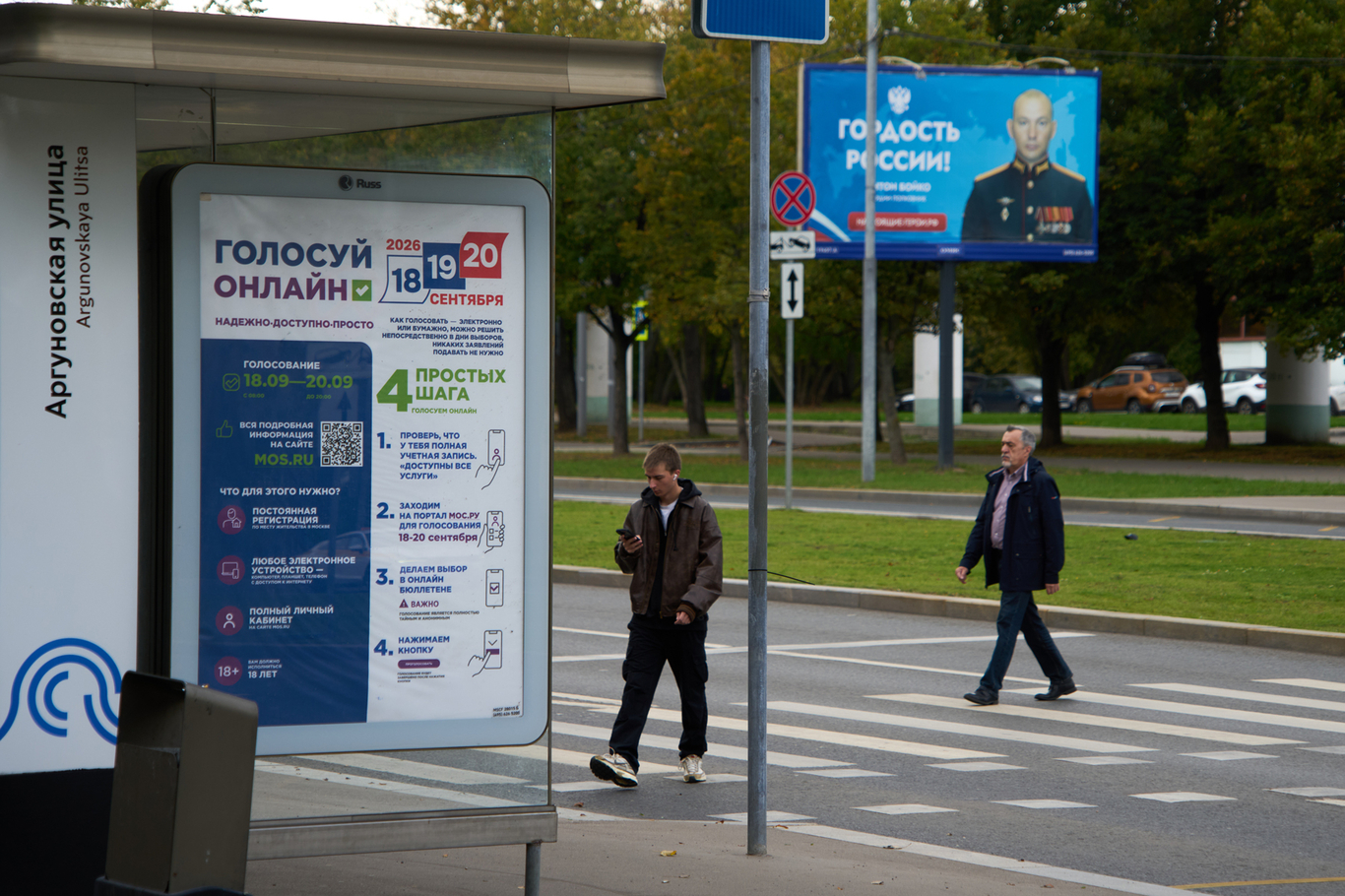 Плакат с призывом голосовать онлайн на парламентских выборах рядом с баннером с изображением российского военнослужащего. Москва. 14 сентября 2026 года. Фото: Александр Земляниченко / AP / Scanpix / LETA