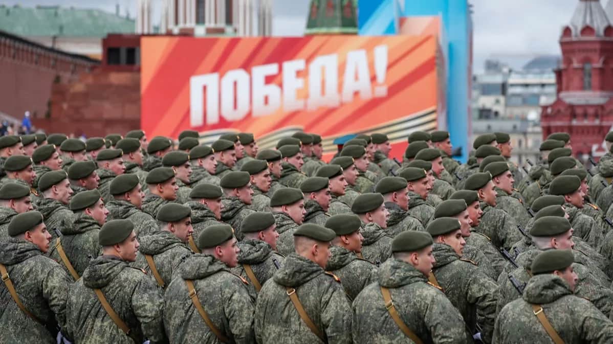 Russian soldiers stand before a poster reading “Victory!” during a rehearsal for Moscow’s Victory Day parade on Red Square, 5 May 2024. Photo: Yuri Kochetkov /EPA-EFE