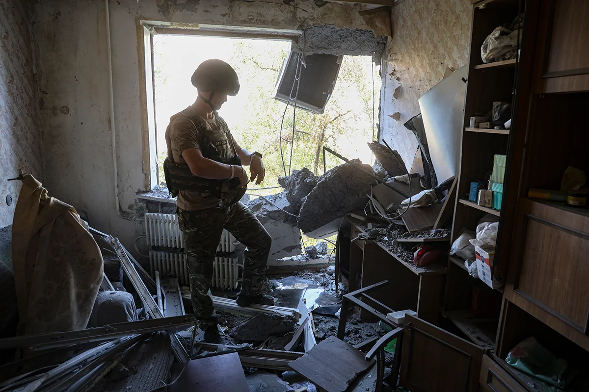 Российский военный осматривает повреждения, причиненные в результате обстрела квартиры в жилом доме в центре Донецка, 16 августа 2024 года. Фото: Alessandro / Guerra / EPA 