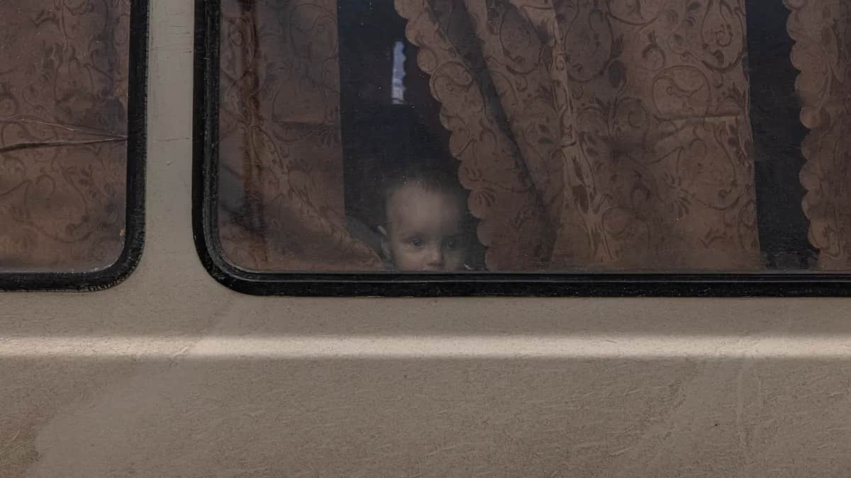 Ребенок выглядывает из микроавтобуса после прибытия из портового города Геническ, Херсонской области. Фото: Роман Пилипей / EPA-EFE