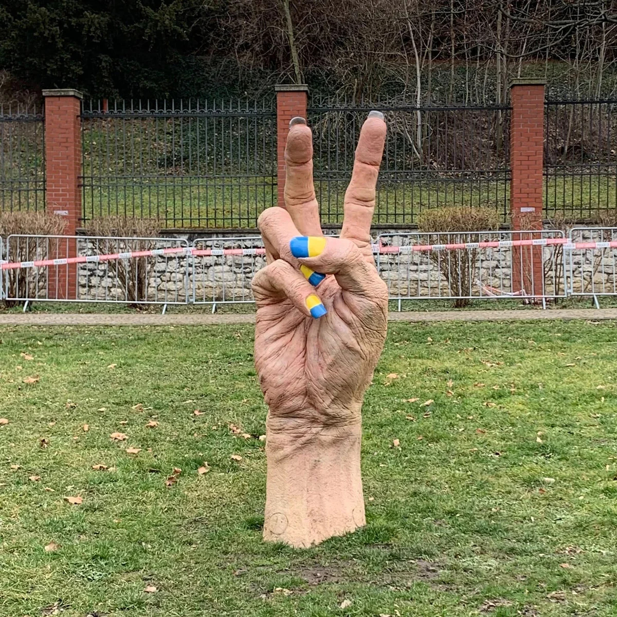 A hand making the peace sign, complete with manicure in the colours of the Ukrainian flag, near the Russian embassy in Prague, Czechia. Photo: Yulia Akhmedova