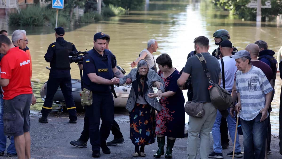 Полицейский помогает пожилой женщине после эвакуации из затопленного района Херсона, 7 июня 2023 года. Фото: Александр Гиманов / AFP / Scanpix / LETA