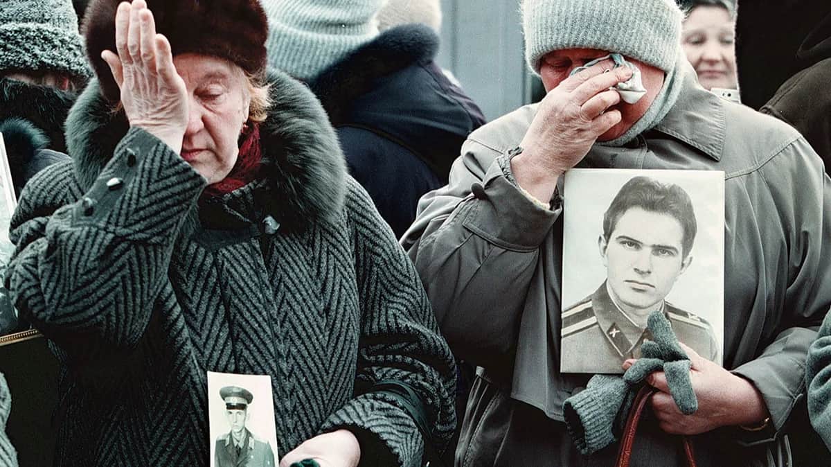 Матери солдат, погибших в российской армии в мирное время, плачут, держа в руках портреты своих погибших детей перед церковью Всех Святых, готовясь к поминальной службе, Москва, Россия, 23 февраля 1999. Фото: Юрий Кочетков / EPA-EFE