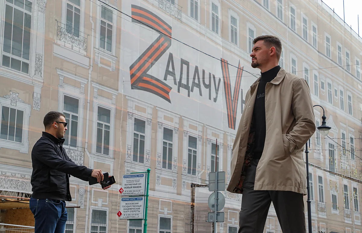 Мужчины около баннера с надписью «Zадачу Vыполним», размещенного на фасаде здания в центре Москвы, Россия, 21 сентября 2022 года. Фото: Максим Шипенков / EPA