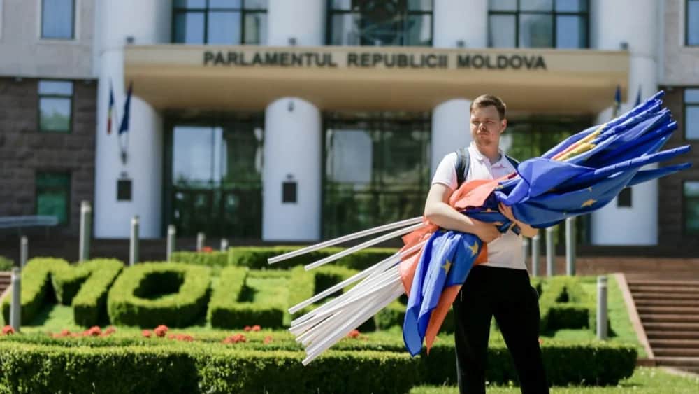 A young man holds flags after a march of PAS Youth, in front of Moldova's Parliament in Chisinau, Moldova, 01 June 2024. Photo: EPA-EFE/DUMITRU DORU