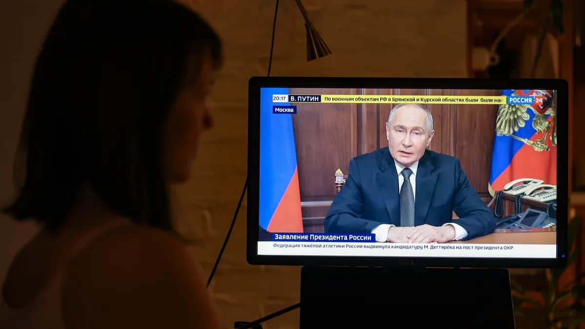 A woman watches Vladimir Putin’s televised address on Thursday evening. Photo: EPA-EFE/SERGEI ILNITSKY