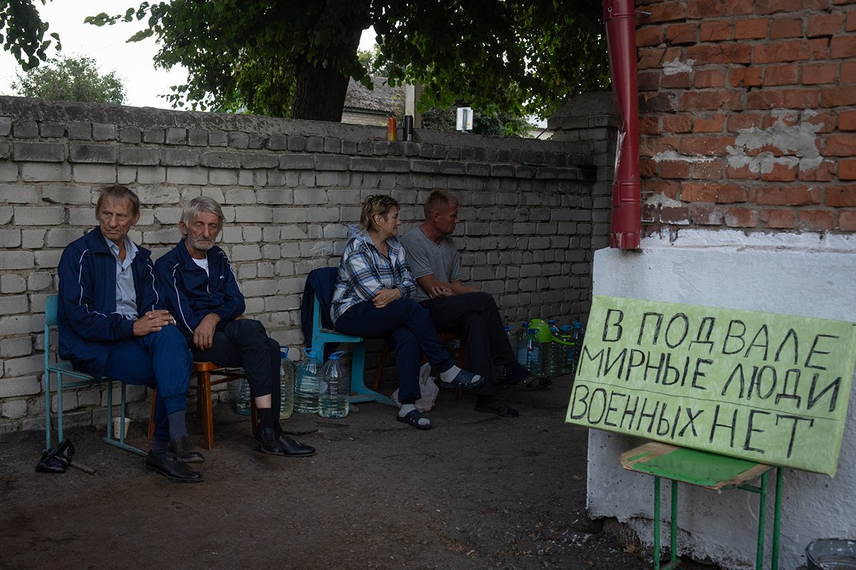 Местные жители возле убежища в Судже, Россия, 16 августа 2024 года, рядом с табличкой с надписью «Гражданские лица в подвале. Военных нет». Фото: AP / Scanpix / LETA