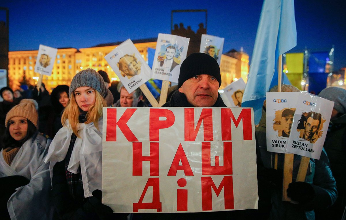 Украинские и крымскотатарские активисты держат плакат с надписью «Крым — наш дом!» и плакаты с именами людей, которые поддерживали Украину и пропали без вести или были арестованы российскими властями в Крыму, во время акции «Солидарность 26» на площади Независимости в Киеве, Украина, 26 февраля 2018 года. Фото: Сергей Долженко / EPA-EFE