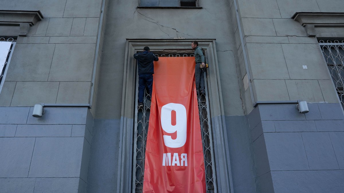 Рабочие устанавливают огромный баннер на заброшенном доме на Ленинградском проспекте. Накануне его частично оштукатурили и выкрасили свежей серой краской.