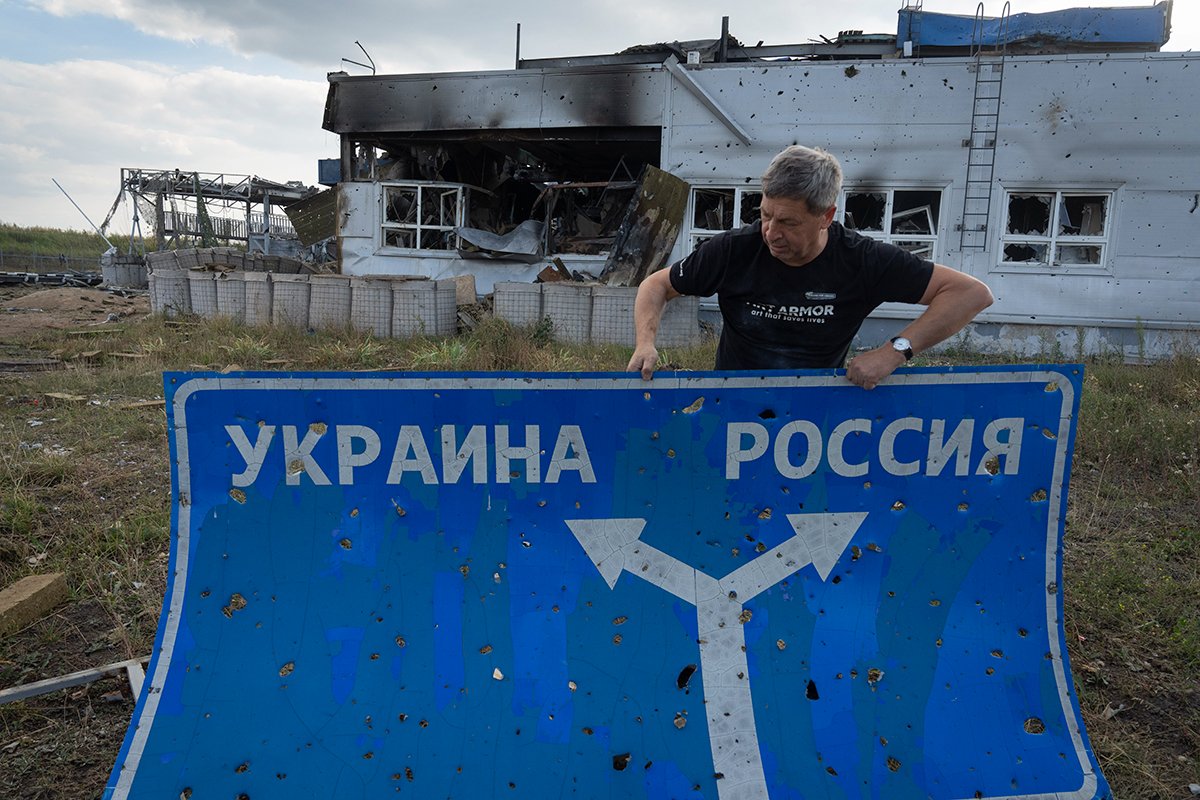 A man holds a bullet-hole riddled road sign showing the direction to Ukraine and Russia, in Sudzha, Russia’s western Kursk region, 16 August 2024. Photo: AP / Scanpix / LETA